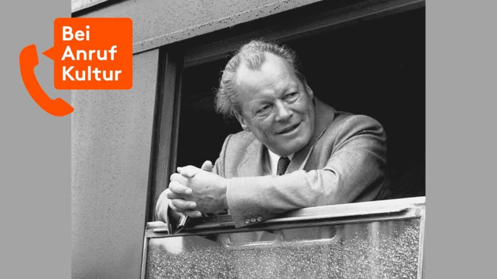 Willy Brandt schaut bei Regen aus einem geöffneten Zugfenster