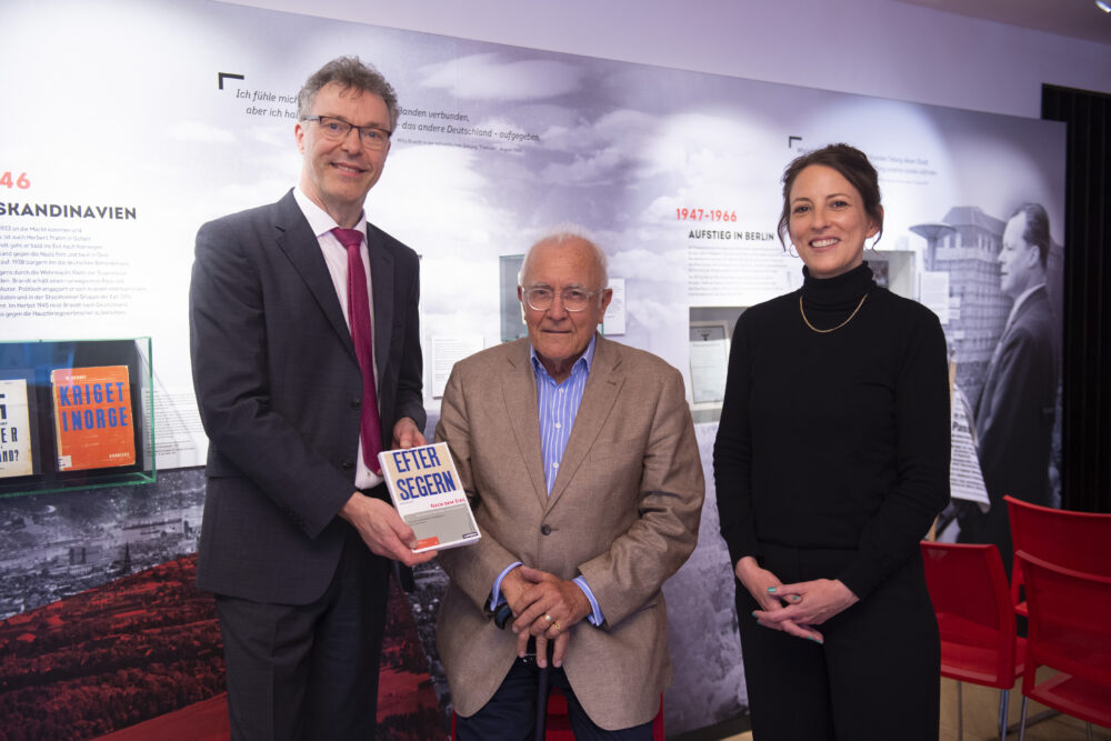 Von links nach rechts stehen Wolfram Hoppenstedt, Bernd Henningsen und Kristina Meyer bei der Buchvorstellung von „Nach dem Sieg“ im Forum Willy Brandt Berlin. Wolfram Hoppenstedt hält eine Ausgabe des Buches in den Händen.