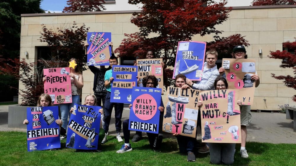 Gruppenbild mit Jugendlichen, die ihre selbstgemachten Ausstellungsplakate hochhalten